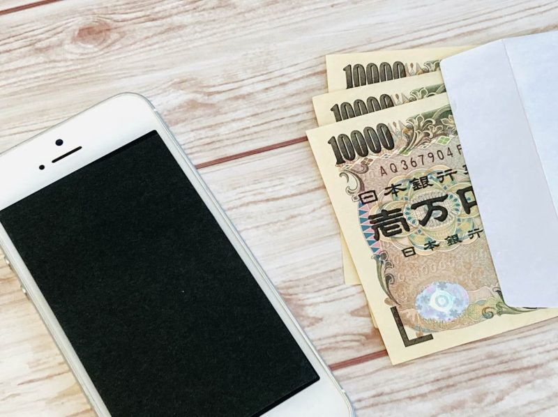 スマホと封筒に入った現金